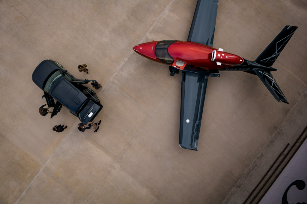 Aerial view of red private jet and SUV